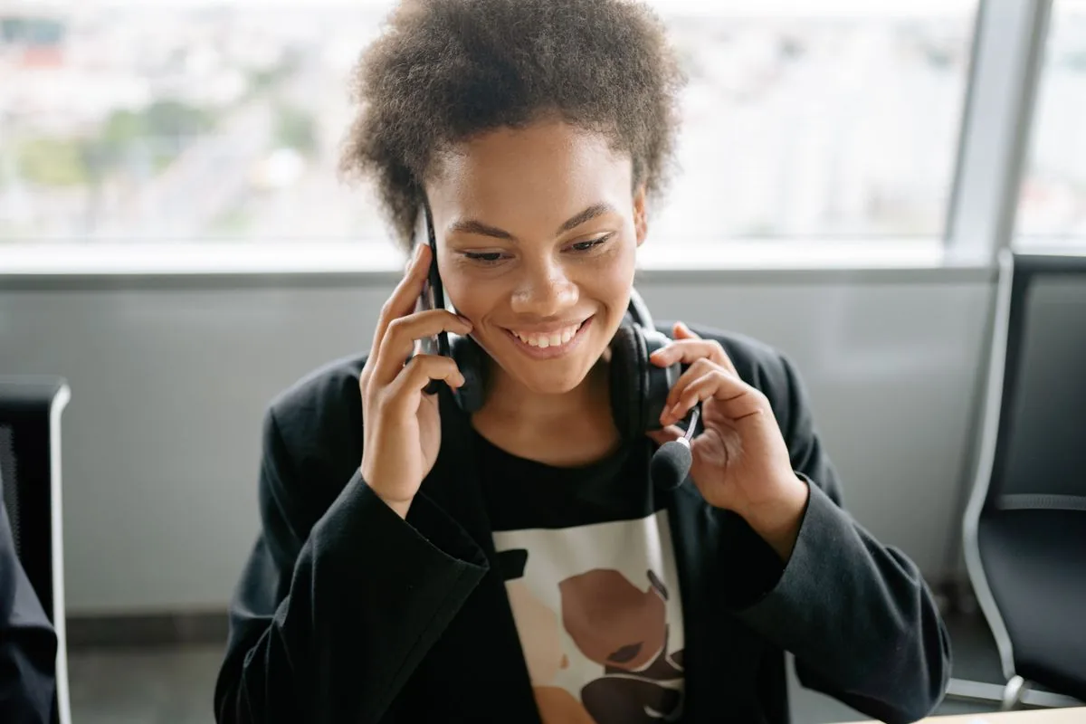 An African customer support agent smiling while on a call with a headset